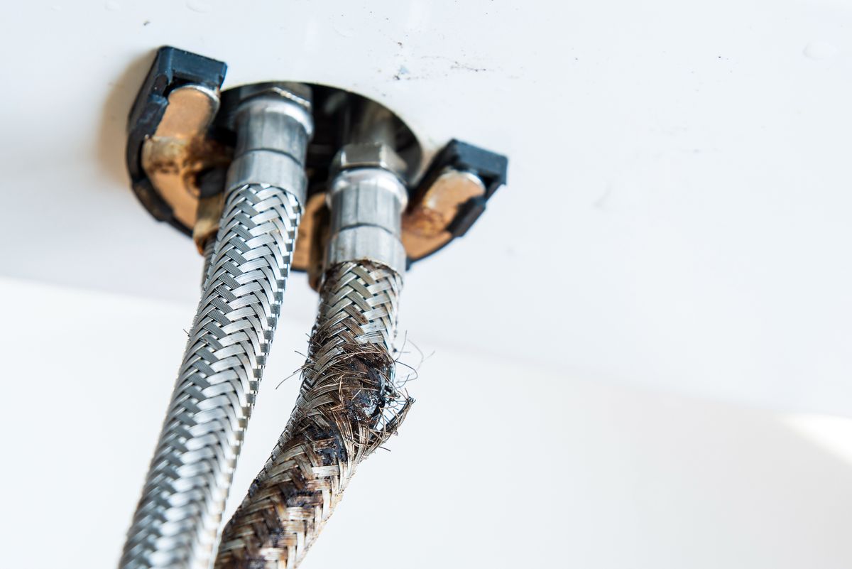 Deteriorating braided flexi hoses showing corrosion and frayed stainless steel braiding